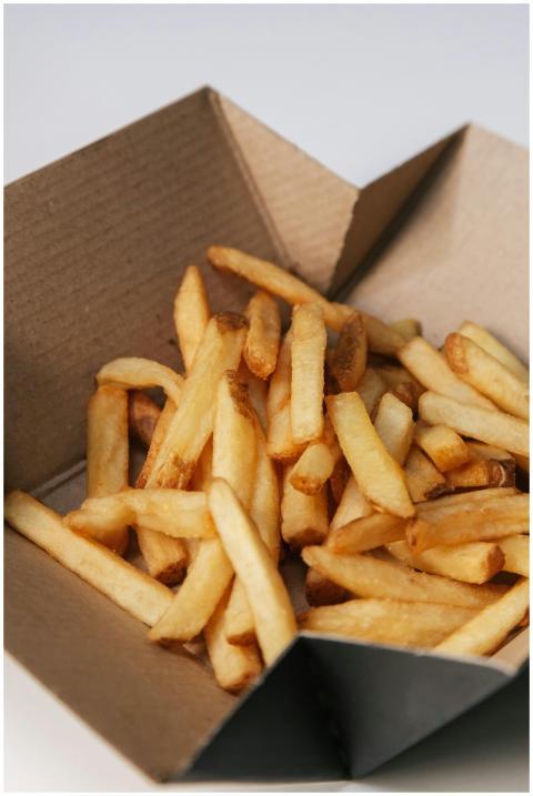 Close-up of golden french fries in a brown cardboa