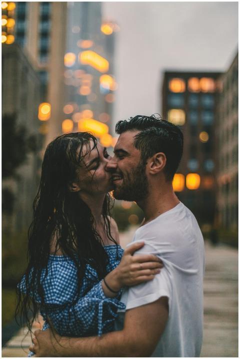 A couple embraces in the rain, surrounded by city