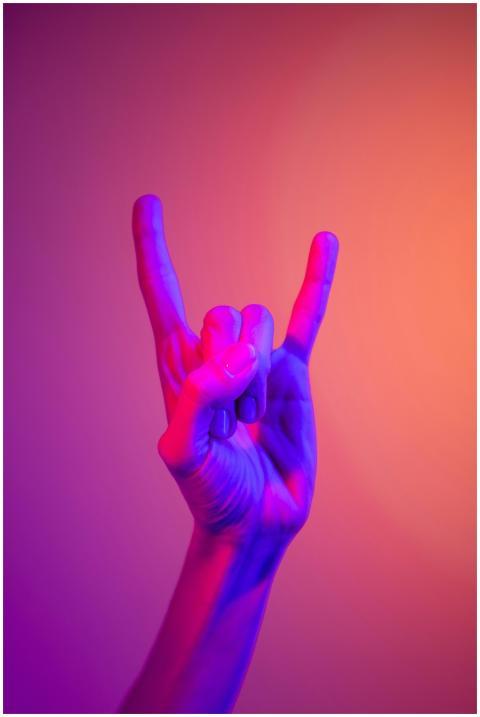A hand showing the rock sign in vibrant neon color