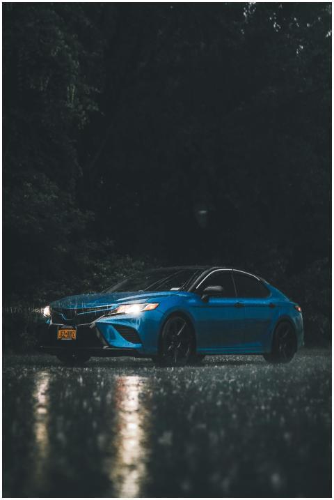 A striking image of a blue car parked in the rain