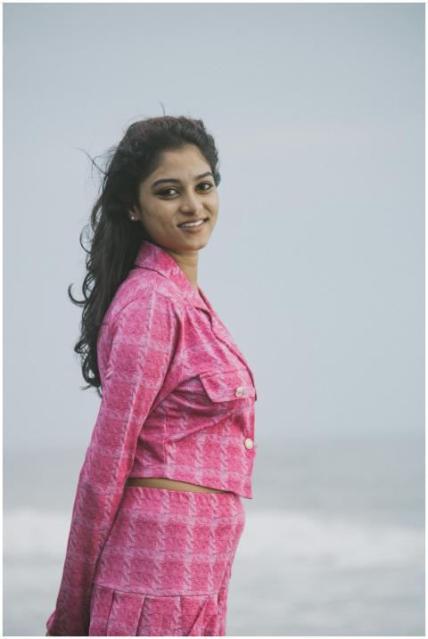 Young woman in a pink outfit smiling at the beach,