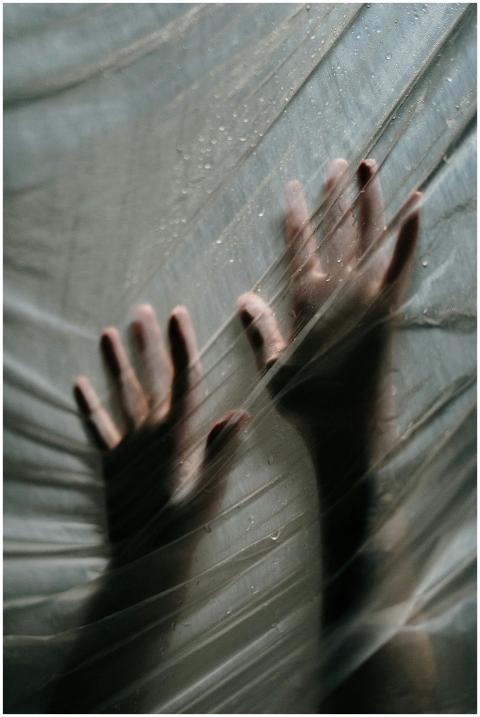 Two hands pressed against translucent plastic, cre