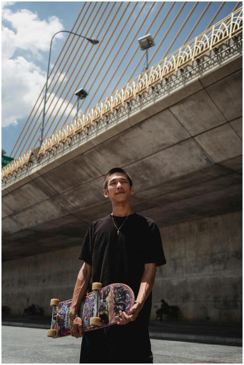 Young contemplative Asian male athlete with skateb