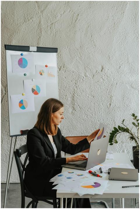 A professional woman examines charts at her desk,
