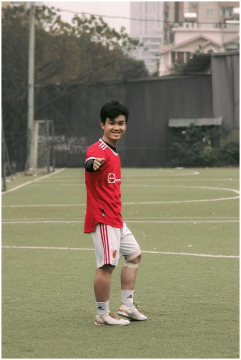 A young male soccer player in a red uniform pointi