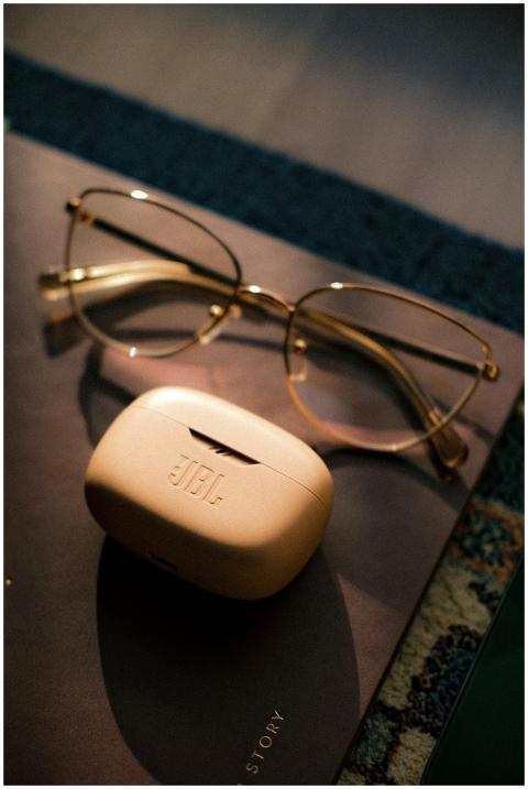 A pair of glasses and JBL headphones rest on a not