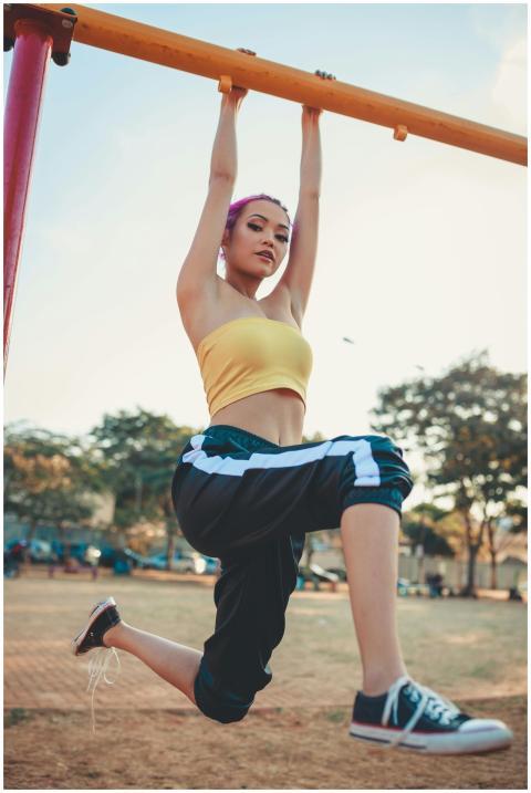 A fit woman in casual activewear hanging from a pl