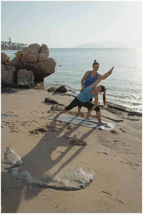 Two women practicing yoga by the sea, enhancing fi