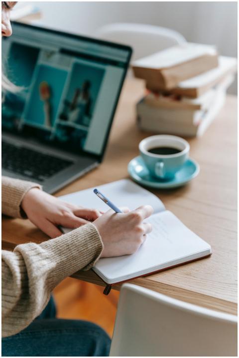 Close-up of a person writing in a notebook beside