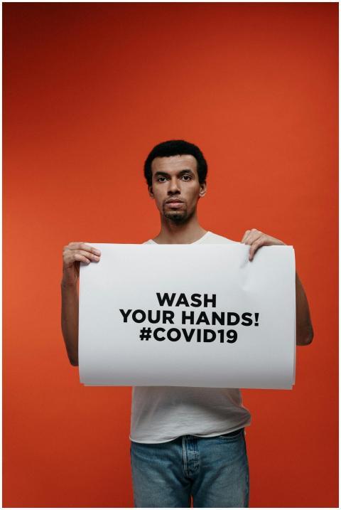 A man holds a 'Wash Your Hands! #COVID19' poster o