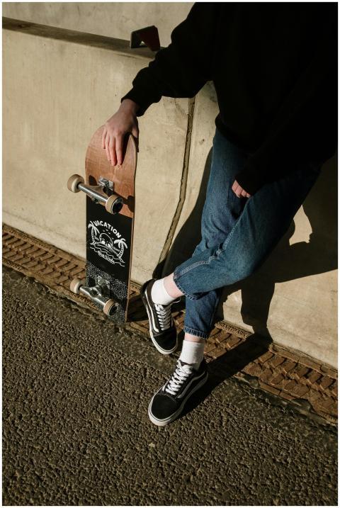 Person wearing jeans and sneakers leaning on a wal