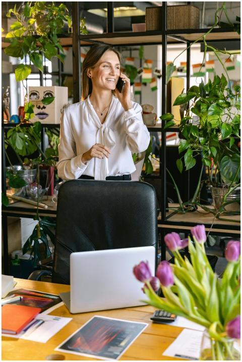 A woman smiling and talking on a phone in a bright