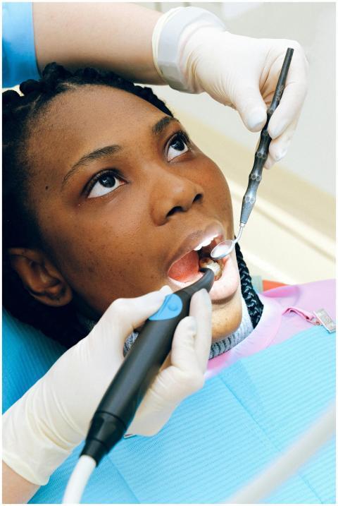 Black woman receiving a dental check-up by a profe