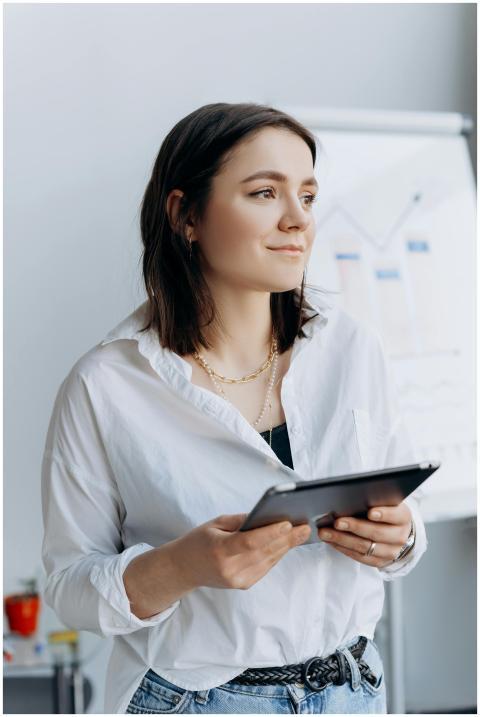 A woman in business attire holding a tablet in a m