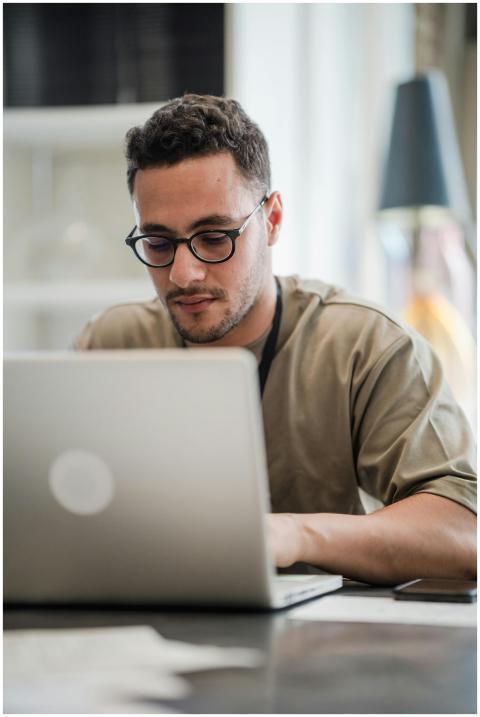 Young man in glasses intensely working on a laptop