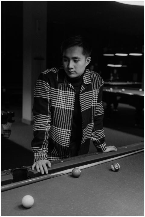 A focused young man at a pool table in a monochrom