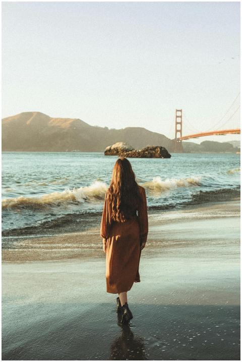 A woman walks along a scenic beach with the Golden