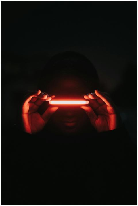 A person enshrouded in darkness holds a glowing re