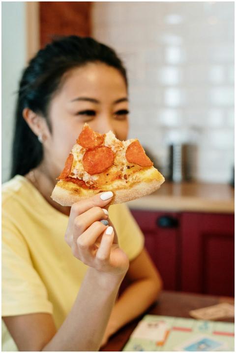 A young woman smiles while holding a piece of pepp