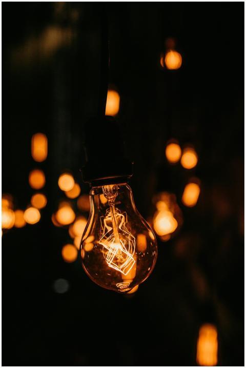 A warmly glowing vintage light bulb in a dark sett