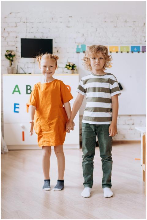 Two children holding hands in a colorful classroom