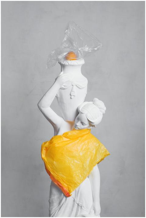 A white statue wrapped in vibrant plastic bags hig