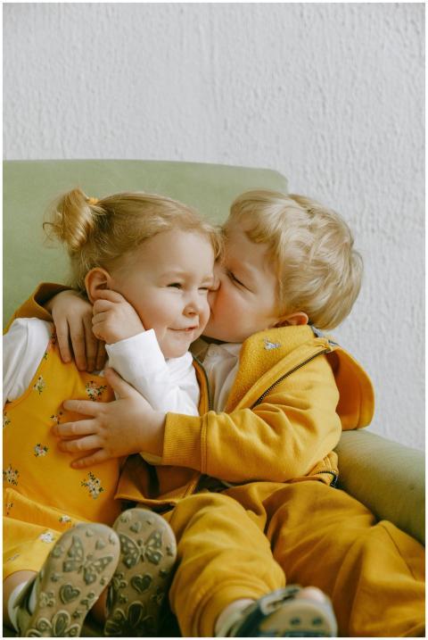 Cute siblings hugging and smiling on an armchair,