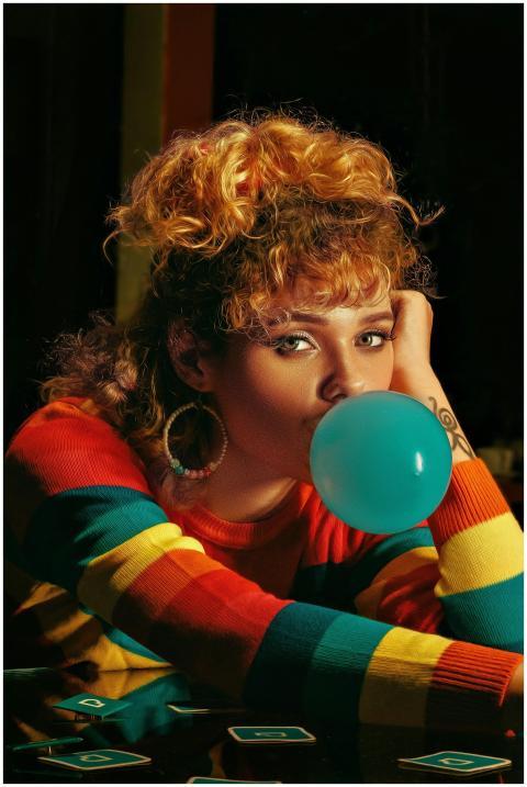 Woman with colorful 80s style blowing bubble gum i