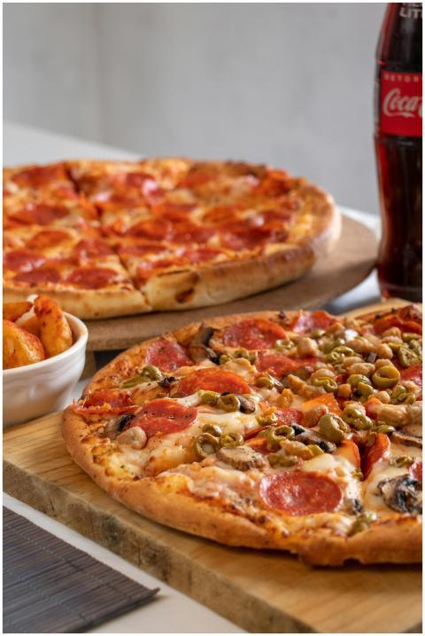 Close-up of pepperoni and veggie pizzas with soda,