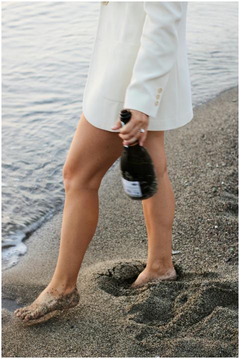 Woman in a white blazer holding a champagne bottle