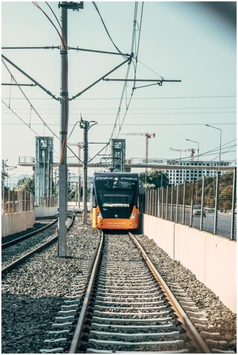 A vibrant orange tram driving on a railway track i