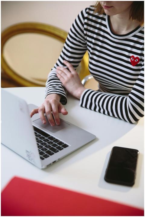 A woman in a striped shirt using a laptop at a des