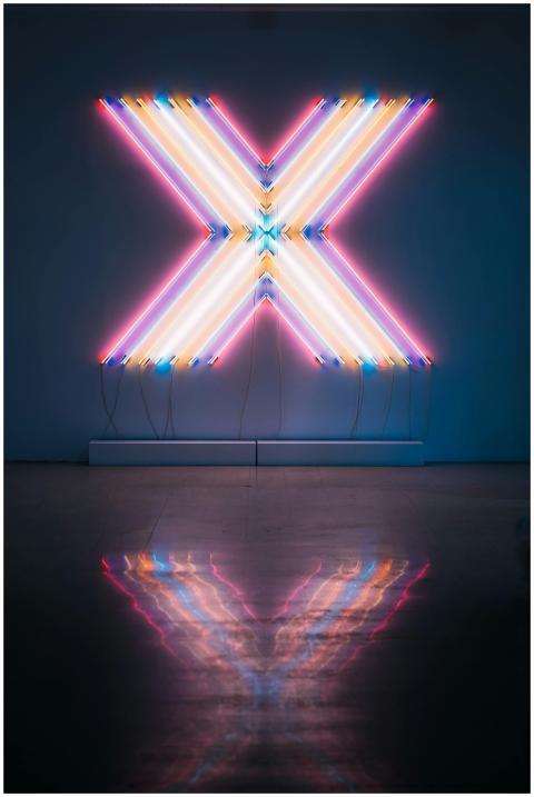 Vibrant neon X sign with colorful reflections on a