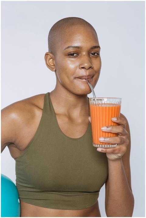 African American woman in a sports bra drinking fr