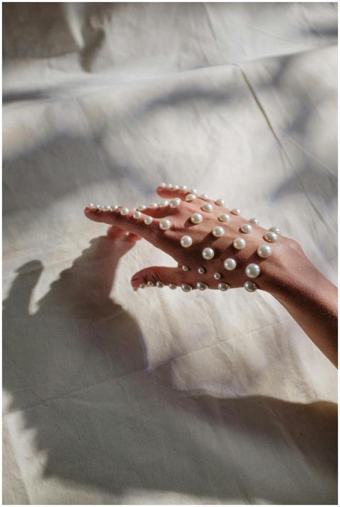 A graceful hand covered in pearls resting on a tex