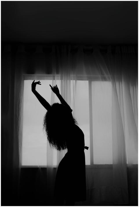 A silhouette of a woman dancing gracefully in fron
