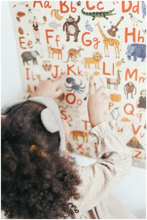 A child points at an educational alphabet and anim