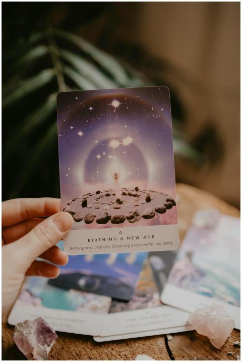 Tarot card held in hand, surrounded by crystals an