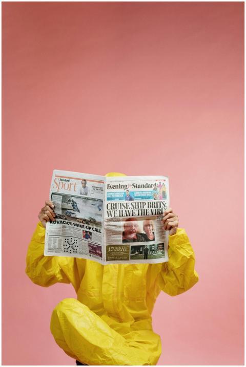 Individual in protective suit reads newspaper with