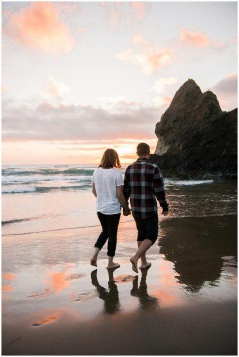 A couple walks hand in hand on the beach at sunset