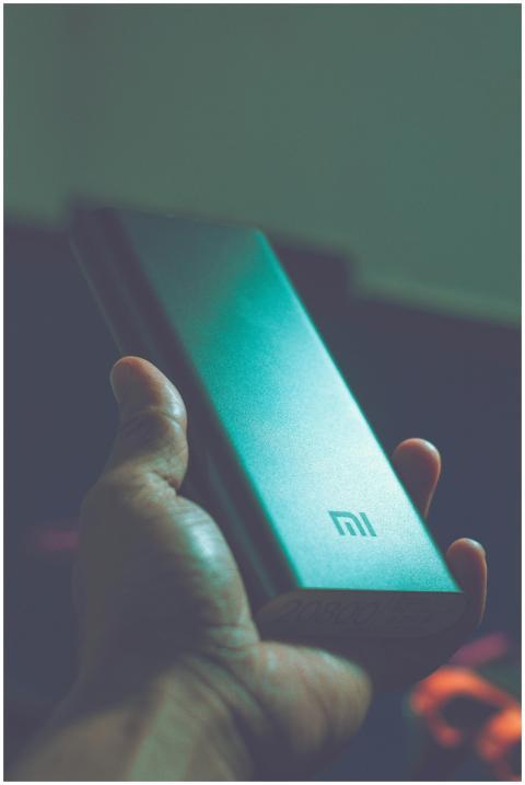 Close-up of a hand holding a Mi power bank, showca