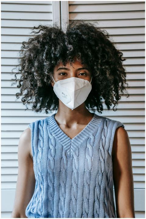 Woman with curly hair wearing a face mask standing
