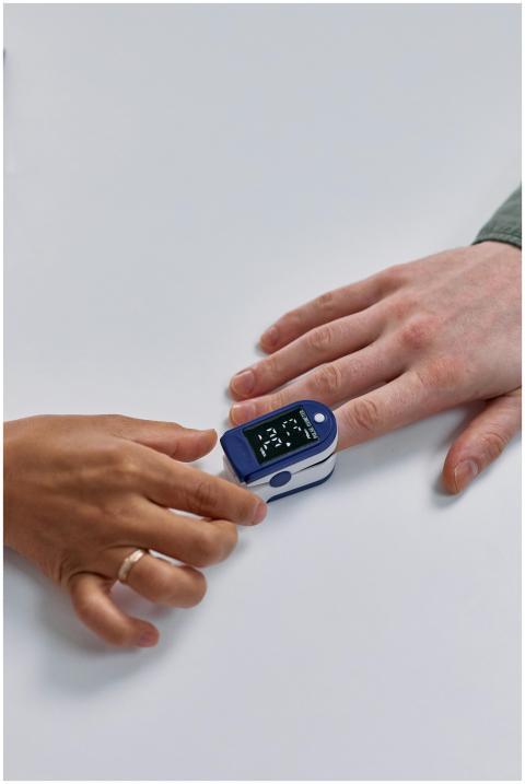 Close-up of a pulse oximeter on a person's finger,