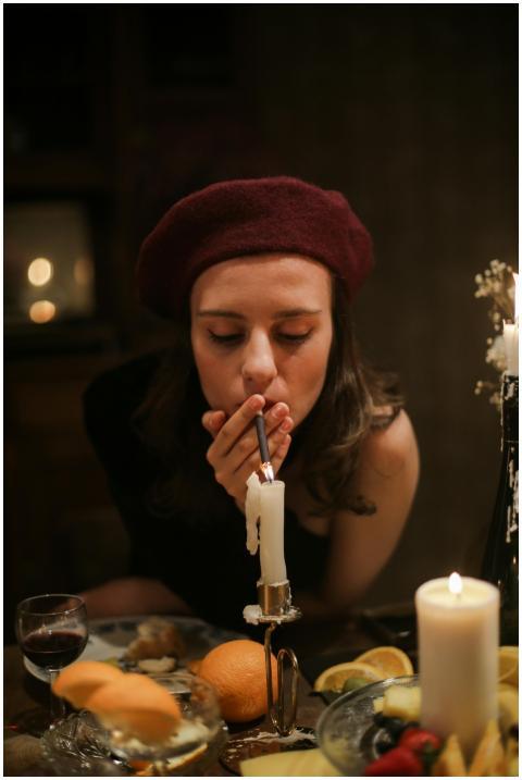 A French girl in beret smokes at a candlelit dinne