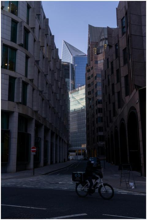 Cyclist in shadowy street with modern skyscraper i