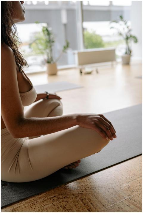 A woman practicing meditation on a yoga mat in a s