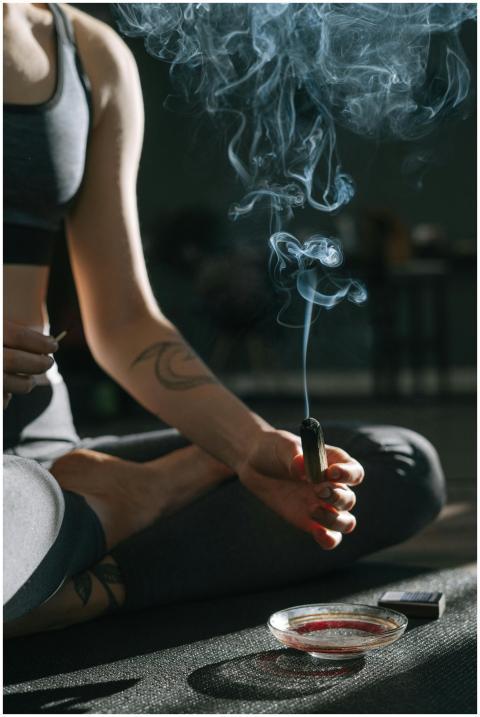 A person practicing meditation holding burning inc