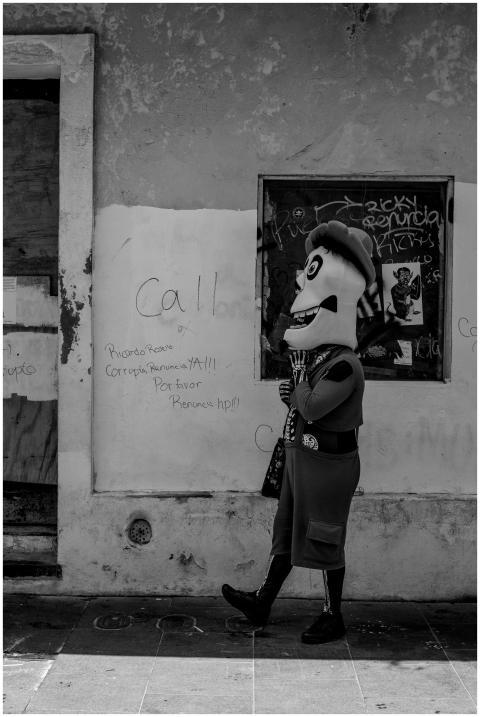A person in a costume walks by a grafitti-covered