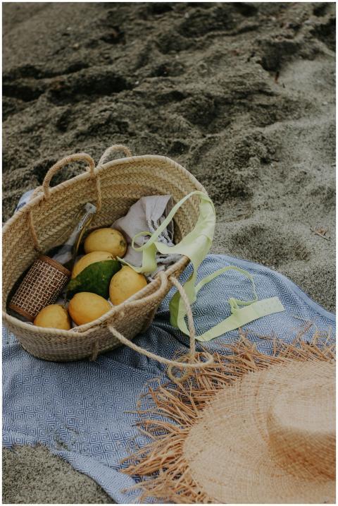 A summer beach scene featuring a picnic basket wit