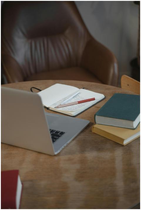 A warm indoor workspace featuring a laptop, notebo